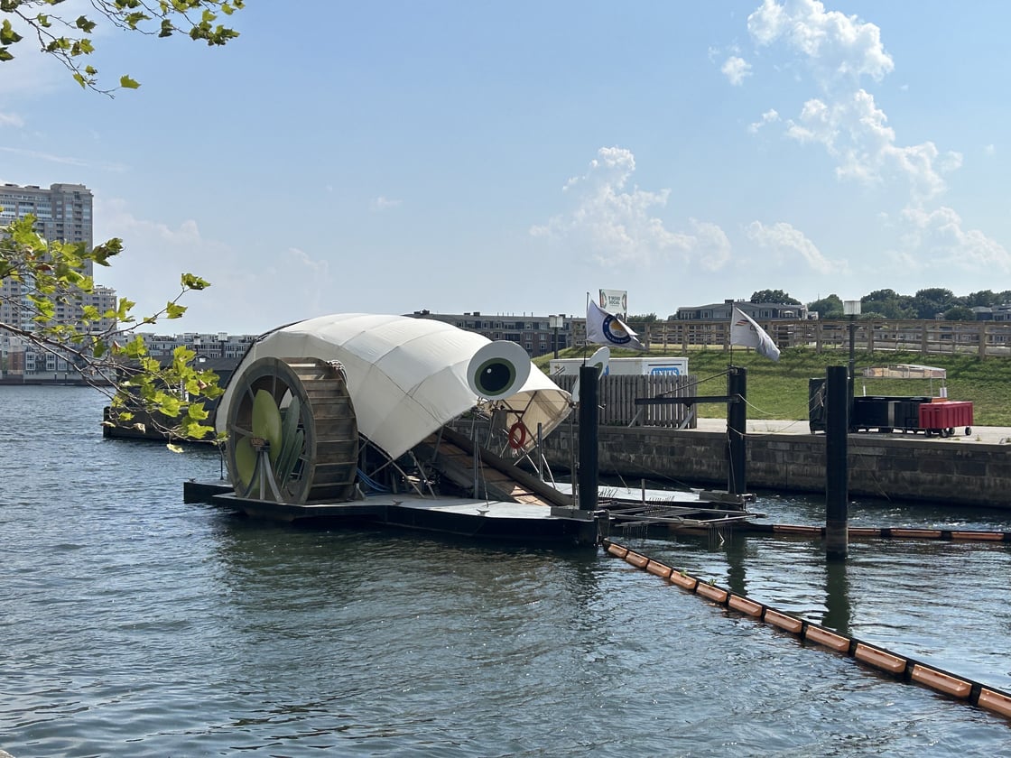 Mr. Trash Wheel, with a white cover, brown wheel and big eyes, in water 