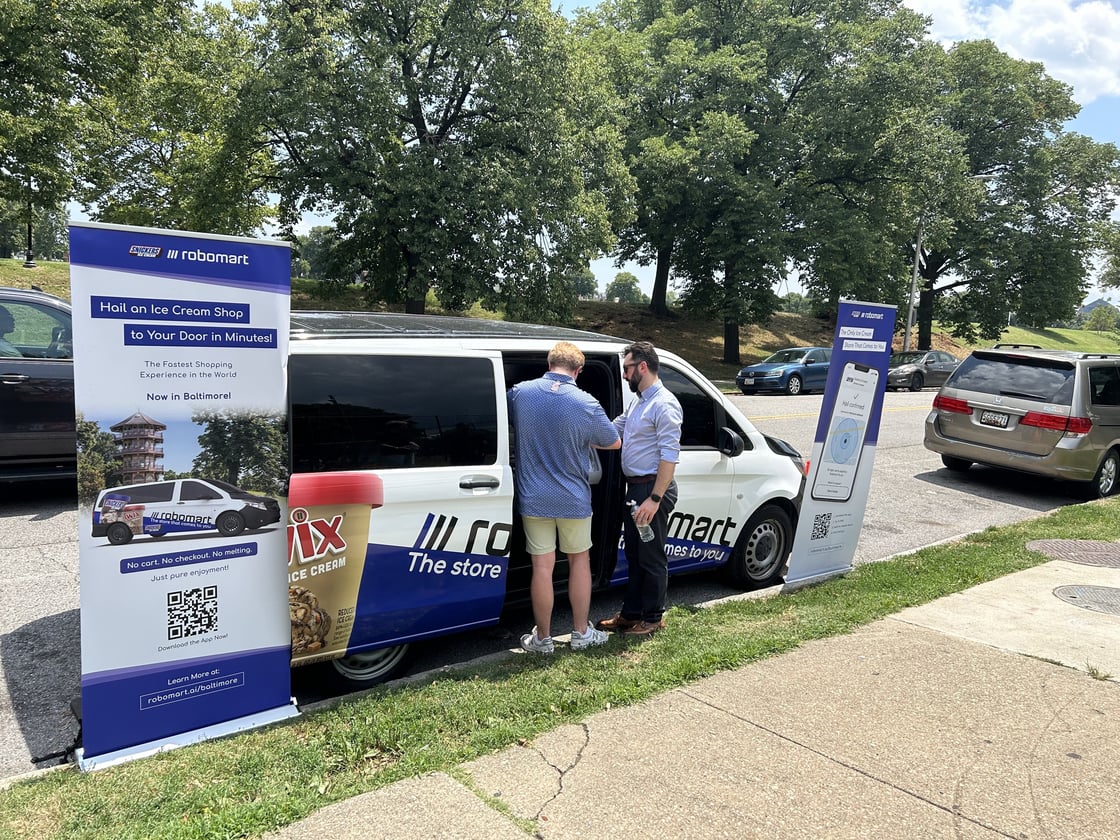 People at blue and white van with Twix logo near a pair of banners