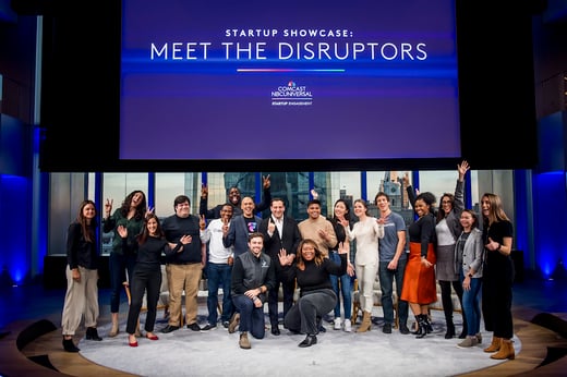 A group of people stand on a stage under a sign that reads 