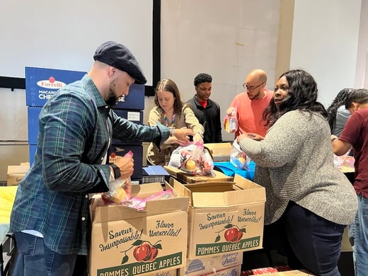 A group of people putting food in boxes at a volunteer event.