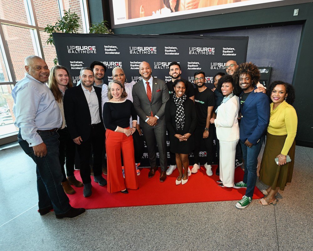 Wes Moore surrounded by people in multicolored professional clothes on a red carpet.