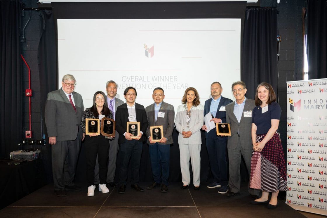 A group of people holding up plaques with a white projection screen behind them.